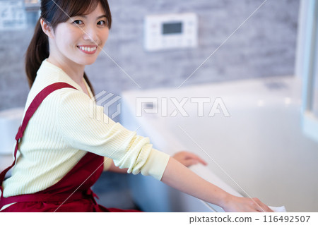 Middle-aged woman in an apron cleaning the bathroom Middle-aged woman in an apron cleaning the bathroom 116492507