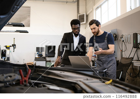 Mechanic and business man discussing car repair in workshop 116492888