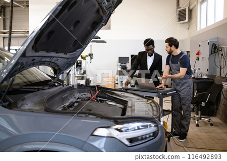Mechanic and businessman discussing car repair in auto shop 116492893