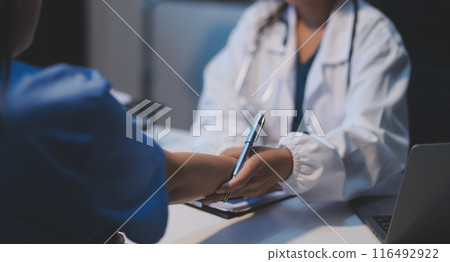 Doctor giving hope. Close up shot of young female physician leaning forward to smiling elderly lady patient holding her hand in palms. Woman caretaker in white coat supporting encouraging old person Doctor giving hope. Close up shot of young female physician leaning forward to smiling elderly lady patient holding her hand in palms. Woman caretaker in white coat supporting encouraging old person 116492922