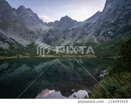 Beautiful alpine lake surrounded by mountains during colorful sunset, Europe, Slovakia Beautiful alpine lake surrounded by mountains during colorful sunset, Europe, Slovakia 116493428