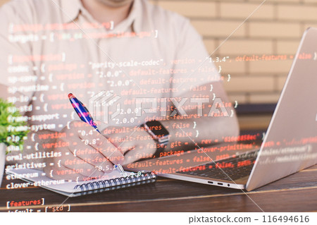 A programmer works with a laptop and writes program code. Software development concept. 116494616