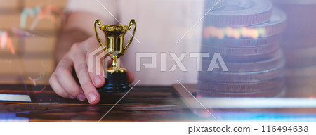 Businessman is using a laptop and holding a golden trophy. Finding the best investment and saving money 116494638