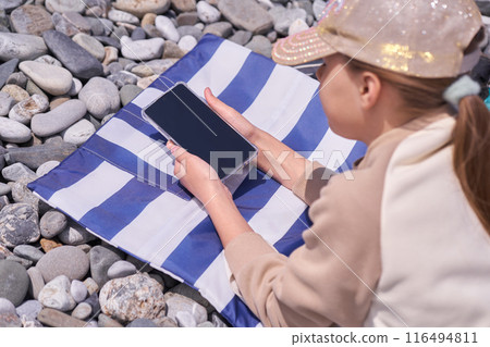 The girl looks at the phone, a mobile app for children with a space to copy. Black screen of a digital device, tablet. High quality photo The girl looks at the phone, a mobile app for children with a space to copy. Black screen of a digital device, tablet. High quality photo 116494811