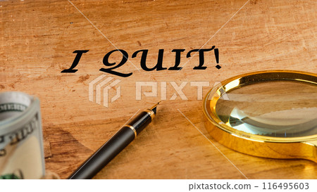 I Quit word on papyrus in a composition with a magnifying glass, fountain pen and dollars without focus 116495603