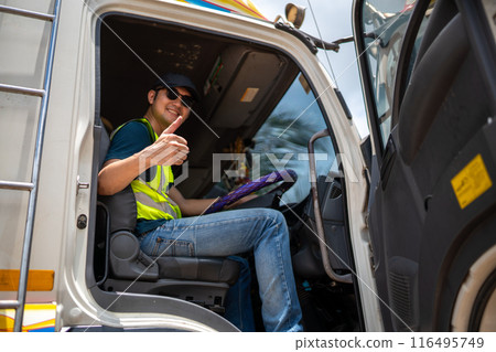 A man in a safety vest is giving a thumbs up while driving a truck A man in a safety vest is giving a thumbs up while driving a truck 116495749