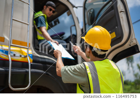 A man in a yellow vest is standing next to a truck and talking to another man A man in a yellow vest is standing next to a truck and talking to another man 116495753