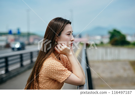 A young woman resting her chin on her hands and looking at the view A young woman resting her chin on her hands and looking at the view 116497187