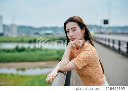 A young woman resting her chin on her hands and looking at the view 116497195