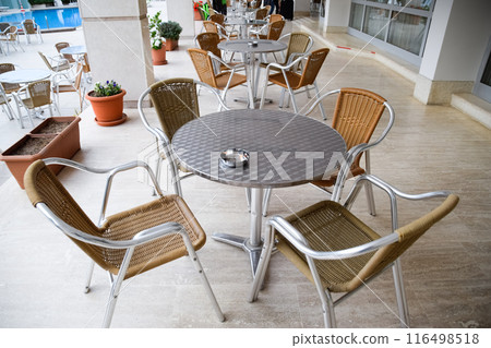 Metal tables and chairs with wicker seats in outdoor cafe. Metal tables and chairs with wicker seats in outdoor cafe. 116498518