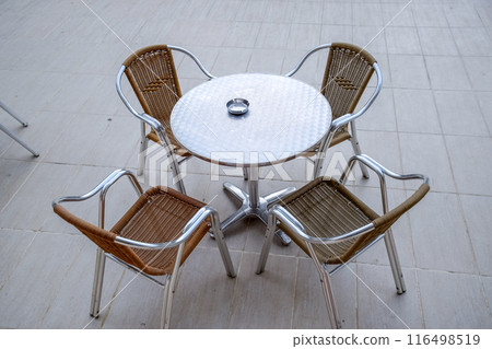 Metal tables and chairs with wicker seats in outdoor cafe. Metal tables and chairs with wicker seats in outdoor cafe. 116498519