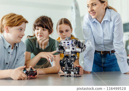 Children learning robotics in Elementary school. Young students building robot in after school robotics club. Field trip to real robotics laboratory. 116499528