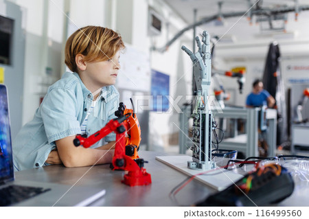 Portrait of schoolboy looking robotic arm and hand, after-school robotics club. Children learning robotics in Elementary school. Science for kids. 116499560