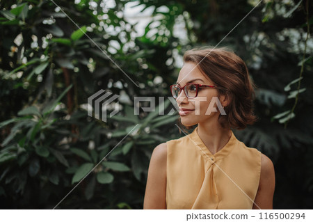 Beautiful woman standing in botanical garden, in the middle of lush green foliage. Beautiful woman standing in botanical garden, in the middle of lush green foliage. 116500294