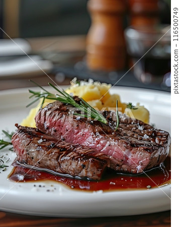 perfectly grilled medium-rare steak with red wine sauce, potato cakes and a cherry tomato on a white plate 116500749