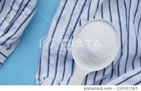 Detergent powder in measuring spoon on cloth before washing. Laundry concept. 116501565