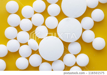 White mothballs on yellow background. 116501575