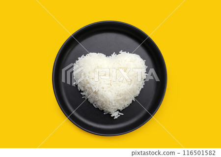 Cooked white rice in black plate on yellow background. Cooked white rice in black plate on yellow background. 116501582