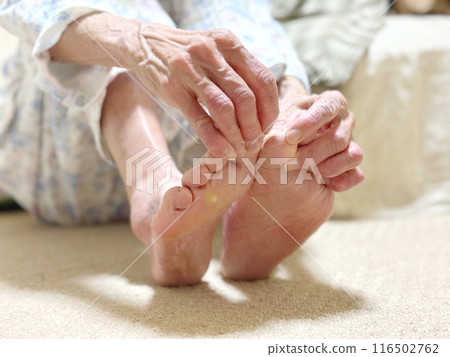 The hand of an elderly woman in pajamas pulling at her toes The hand of an elderly woman in pajamas pulling at her toes 116502762