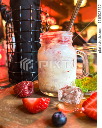 Mason jar with ice cream and fresh raspberries on wooden table. Delicious yogurt with fresh berries in a jar  116502812