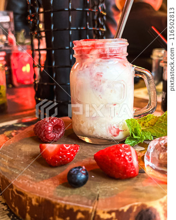 Mason jar with ice cream and fresh raspberries on wooden table. Delicious yogurt with fresh berries in a jar  116502813