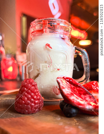 Mason jar with ice cream and fresh raspberries on wooden table. Delicious yogurt with fresh berries in a jar  116502815