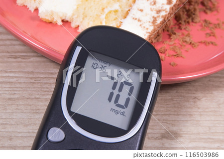 Glucose meter with good result of sugar level and cake with layers and chocolate 116503986