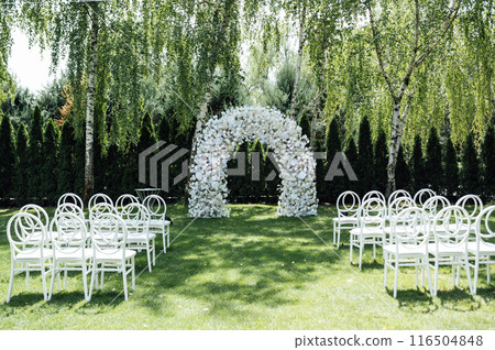 Wedding ceremony. Very beautiful and stylish wedding arch, decorated with various fresh flowers, standing in the garden. 116504848