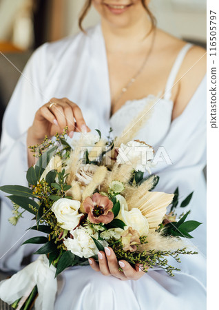 Boudoir photo of a beautiful girl with long hair. Flowers in the hands of a beautiful woman. Boudoir photo of a beautiful girl with long hair. Flowers in the hands of a beautiful woman. 116505797