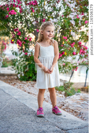 Little girl in white dress happy smiling on blooming park background in Croatia Little girl in white dress happy smiling on blooming park background in Croatia 116506379