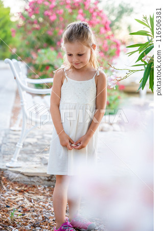 Portrait of little girl in white dress happy smiling on blooming park background in Croatia Portrait of little girl in white dress happy smiling on blooming park background in Croatia 116506381