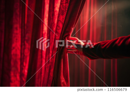 Hand opens red curtain on stage, revealing backstage area 116506679