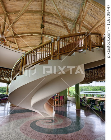 There is a spiral staircase in a building with a wooden railing 116508447