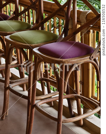 A row of chairs made of wood with cushions in purple and green colors A row of chairs made of wood with cushions in purple and green colors 116508532