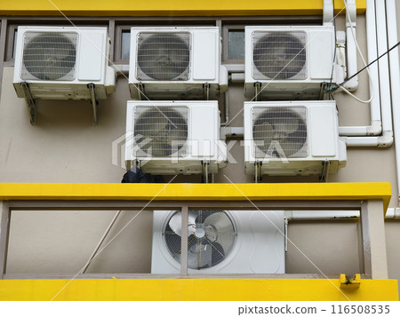 There are numerous air conditioners installed on the exterior of the building There are numerous air conditioners installed on the exterior of the building 116508535