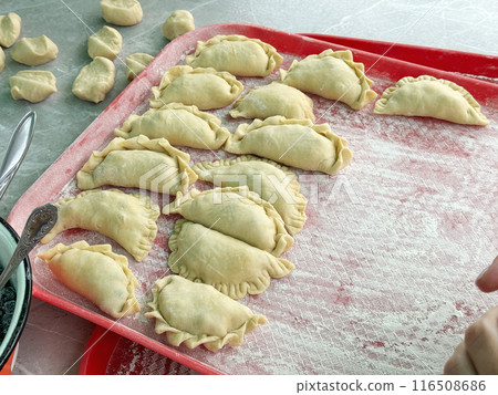 Cooking dumplings with blueberries. Dumplings are laid out on a tray. 116508686
