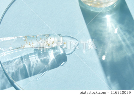 Serum gel texture swatch. Transparent drop golden sparkles. Blue background Serum gel texture swatch. Transparent drop golden sparkles. Blue background 116510059