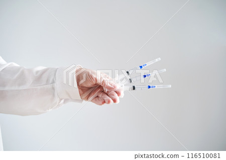 The doctor's hands in a white coat and gloves hold three syringes with medicine. 116510081