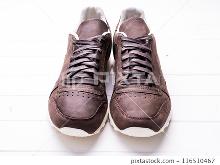 brown leather shoes with laces on wooden background 116510467