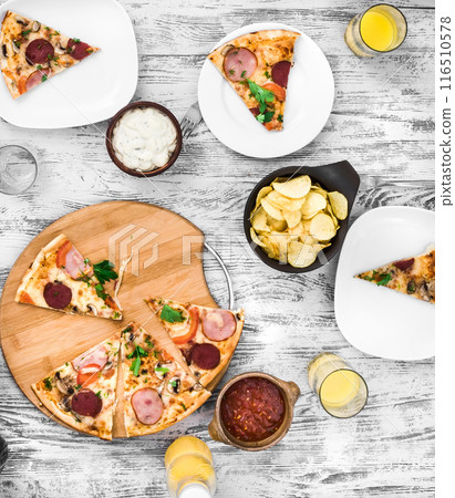 dinner with pieces of pizza on board and plates 116510578