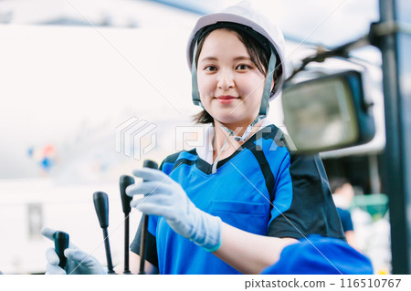A woman in a helmet driving a forklift 116510767