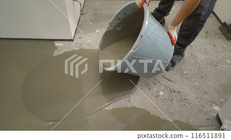 The self-leveling floor solution is poured onto the floor. A worker pours self-leveling solution to level the floor. Self-leveling floor. Floor leveling solution. 116511891
