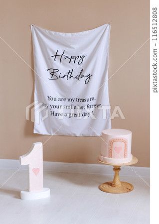 A white banner with the words Happy Birthday written on it hangs on a wall A white banner with the words Happy Birthday written on it hangs on a wall 116512808