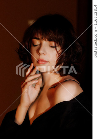 A woman stands in front of a wall with a shadow, creating a dramatic atmosphere A woman stands in front of a wall with a shadow, creating a dramatic atmosphere 116512814