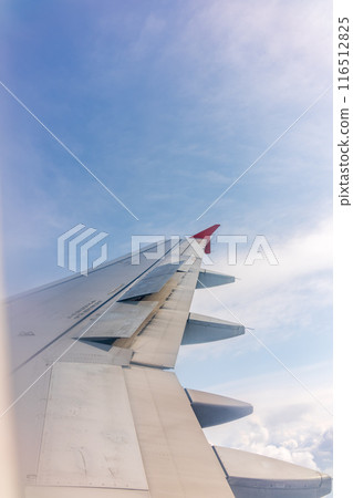 View from the airplane window at a beautiful cloudy sky and the airplane wing View from the airplane window at a beautiful cloudy sky and the airplane wing 116512825