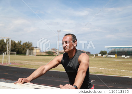 Man Stretching His Arms In The Athletic Track  116513555