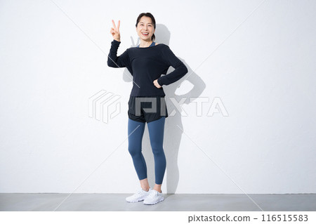 A full-body image of a woman who values exercise and health. Peace sign A full-body image of a woman who values exercise and health. Peace sign 116515583