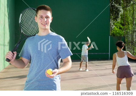 Portrait of caucasian boy standing on frontenis court, holding racket and ball Portrait of caucasian boy standing on frontenis court, holding racket and ball 116516309