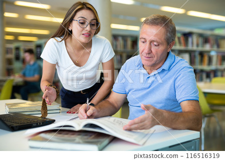 Young female Latina tutor teaching a mature caucasian elder 116516319