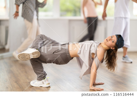 Young girl breakdancing against background of group members Young girl breakdancing against background of group members 116516444